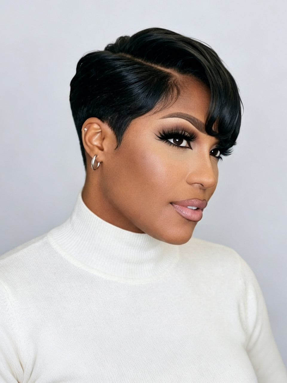 A woman with a short, styled black wig or hairpiece, wearing a white turtleneck sweater against a light gray background.