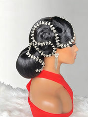 A side profile of a mannequin wearing a dramatic black updo hairstyle decorated with silver leaf-patterned headbands and dangling silver earrings, paired with a bright red top against a light gray background.