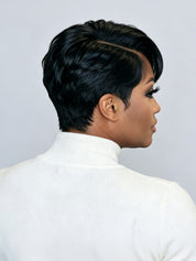 A woman shown from the back and side profile wearing a short, dark, textured wig with a side part, styled with dramatic false eyelashes and a white turtleneck sweater against a light gray background.