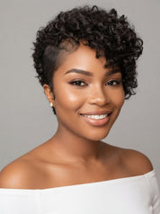 A smiling woman with short, curly black hair wearing a white off-the-shoulder top against a plain gray studio background.