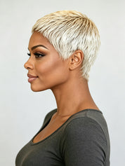 A woman shown in side profile wearing a short, textured pixie cut wig in a platinum blonde shade, paired with a dark gray scoop-neck top, against a plain light gray background.