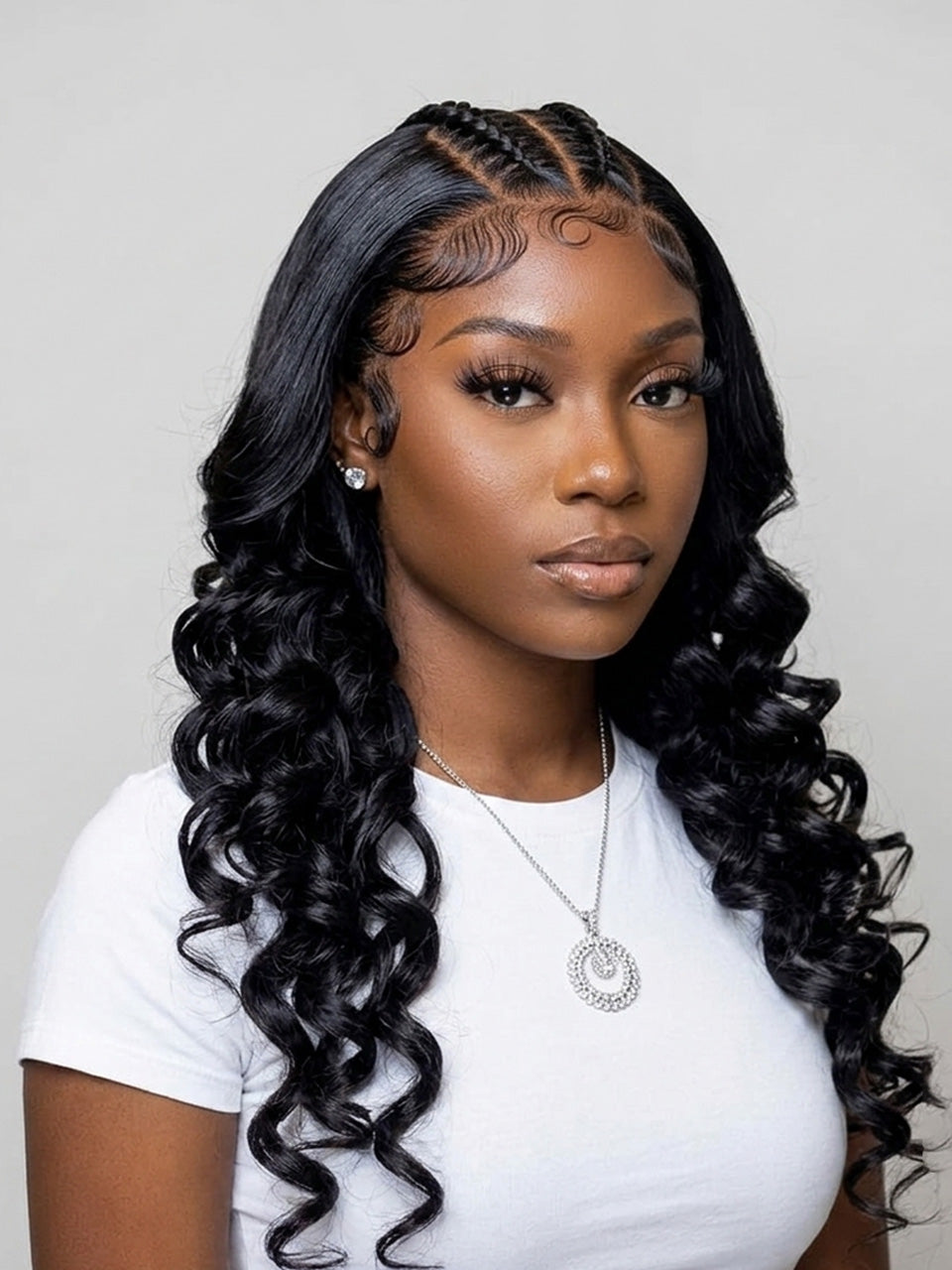 A woman with long, glossy, black, body-wave hair styled with cornrow braids at the top, wearing a white t-shirt and a silver necklace against a light gray background.