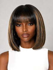 A woman wearing a straight, shoulder-length bob wig with bangs. The wig has a dark brown to black base with warm caramel and light brown highlights, styled against a neutral gray background.
