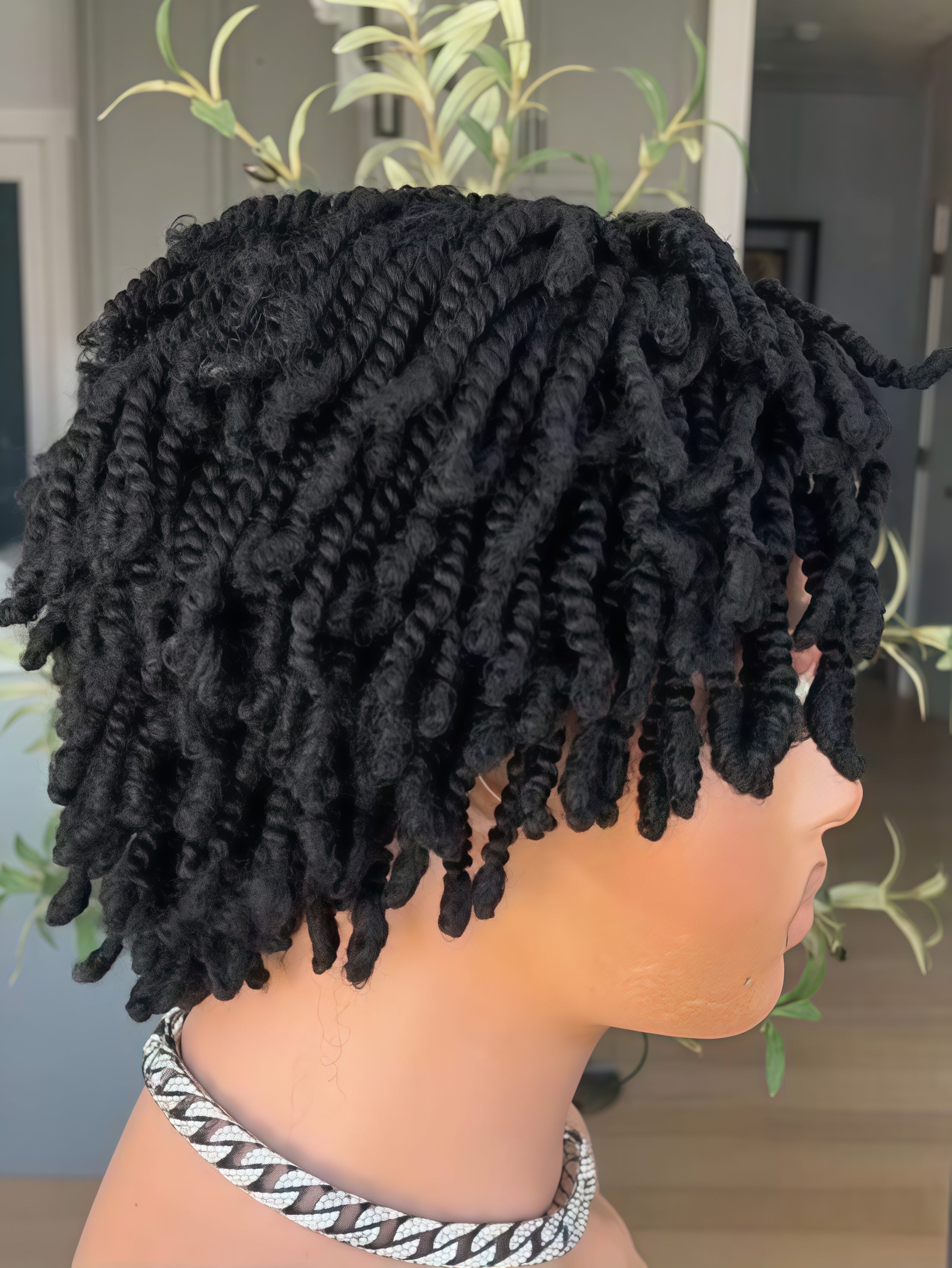 Black twisted loc hair extensions styled on a mannequin head, shown from a side profile view with a silver chain necklace.