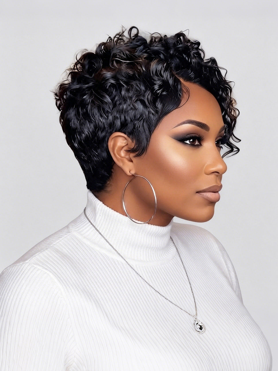 A woman shown in profile wearing a short, curly black wig, a white ribbed turtleneck sweater, large silver hoop earrings, and a delicate silver necklace against a light gray studio background.
