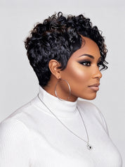 A woman shown in profile wearing a short, curly black wig, a white ribbed turtleneck sweater, large silver hoop earrings, and a delicate silver necklace against a light gray studio background.