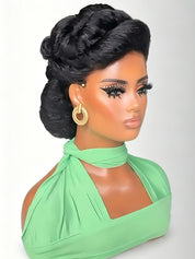 A black synthetic braided wig styled in an elegant updo with twisted braids and ringlets, displayed on a mannequin bust wearing a mint green halter top and gold hoop earrings against a light gray background.