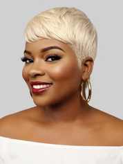 A woman with a short, textured platinum blonde wig, styled with gold hoop earrings and a white off-the-shoulder top, shown against a solid gray background.