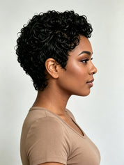 A woman shown in side profile wearing a short, curly black wig against a plain light gray studio background.