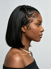 A woman in profile wearing a short, straight black wig with braided detailing along the crown and a pearl necklace against a light gray background.