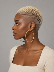 A woman in profile wearing large gold hoop earrings with a beaded texture, a short textured blonde haircut, and a cream ribbed top against a solid gray background.