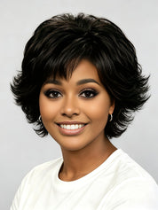 A smiling woman with short, layered black hair wearing a white top against a light gray studio background.