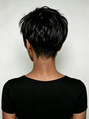 Rear view of a person with a short, layered black pixie cut, wearing a black short-sleeve top against a light gray background.
