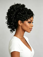 A woman in profile wearing a short, voluminous black curly wig against a light gray studio background.