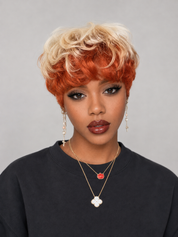 A woman wearing a short, curly wig with a two-tone color scheme of bright orange and blonde, paired with a black crewneck sweatshirt and layered gold necklaces.