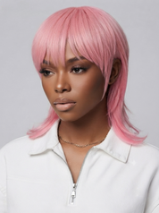 A woman wearing a short pink wig with straight bangs, styled with side-swept bangs and layered ends, paired with a white zip-up top against a light gray background.