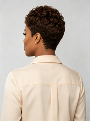 A woman with a high-volume curly wig or hair extension styled in a half-up ponytail with defined side parting, shown in a close-up portrait against a light gray studio background.